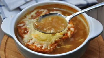French onion soup with spoon in bowl.