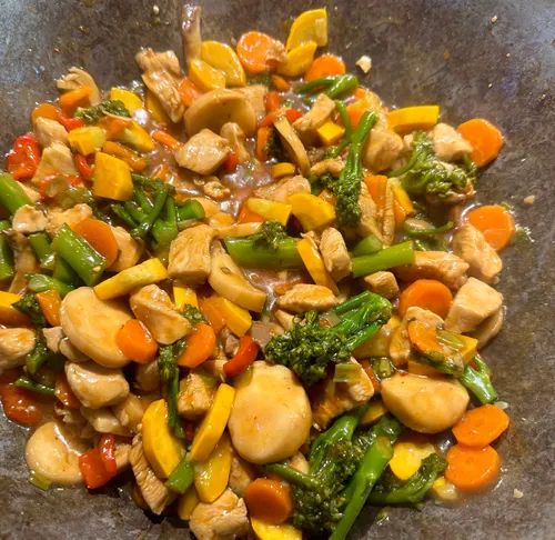 Chicken stir-fry with vegetables in pan.
