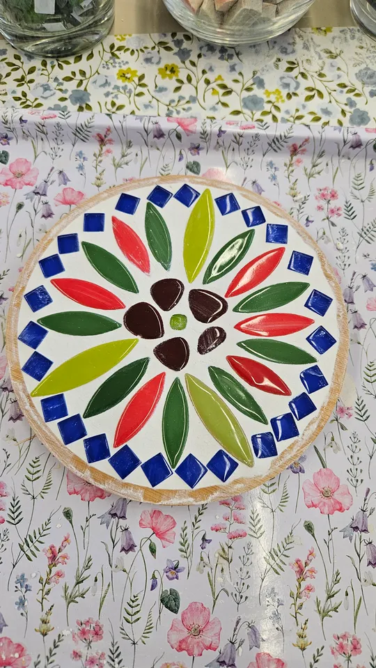 Dekorative Mosaikschale auf Blumenmuster-Tischdecke.