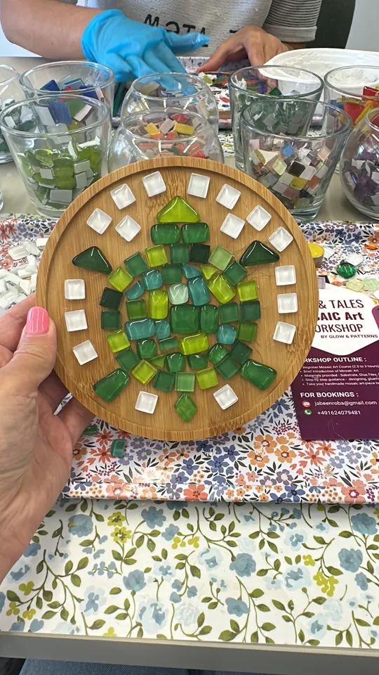 Hand hält Mosaikschildkröte, Werkstattumgebung.