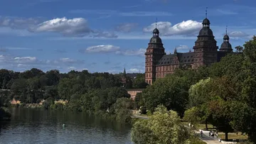 Castle overlooking river surrounded by trees.