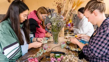 Menschen gestalten Blumengestecke an einem Tisch.