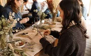 Frau arrangiert Trockenblumen, Indoor-Workshop.