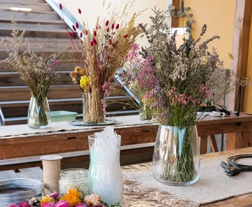 Dried flowers arranged in glass vases on wooden table.