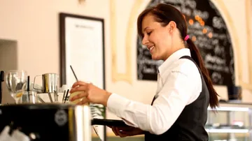 Kellnerin serviert Getränke in einem Café.