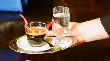 Tray with coffee, red chili peppers, glass of water.