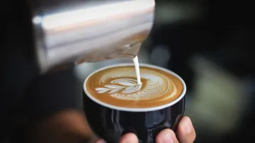 Kaffeetasse mit Milch, die Latte Art erzeugt.
