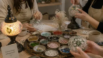 Personen basteln Mosaiklampen am Holztisch.
