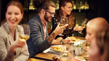 Menschen beim Essen, halten Weingläser, Innenraum.