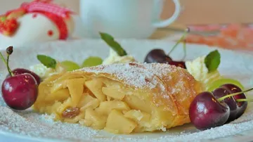 Apple strudel with cherries on plate.