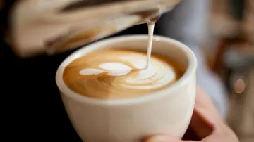 Latte art being poured into a mug.