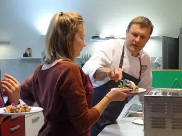 Koch serves a meal to a waiting person.
