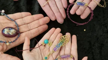 Hände zeigen handgefertigten Schmuck auf Stoff.