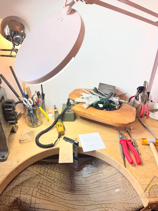 Werkbank eines Juweliers mit Werkzeugen und Lampe.