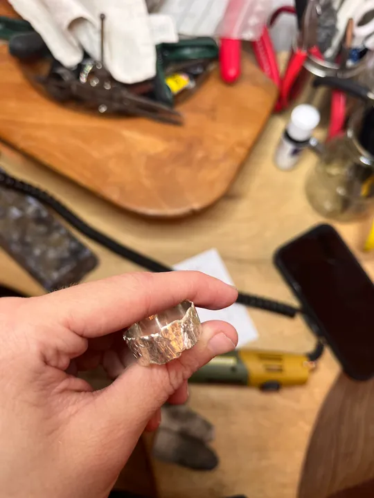 Hand hält Ring, umgeben von Werkzeugen.