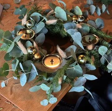 Decorative wreath with candles on table.