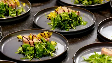 Plates with arugula, meat, mango garnish.