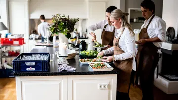 Chefs preparing salads in a kitchen.