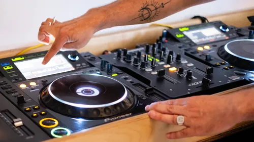 DJ passt Mixersteuerungen auf Holztisch an.