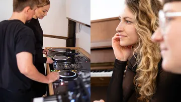 Zwei DJs mixen Musik drinnen. Frau hört zu.