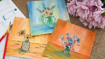 Flower paintings displayed on wooden table.