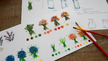 Watercolor flowers and brushes on paper.