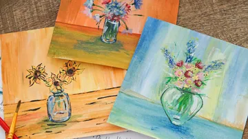 Three floral paintings on a wooden surface.