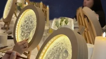 Personen malen auf beleuchtetem Leinwand beim Abendessen.