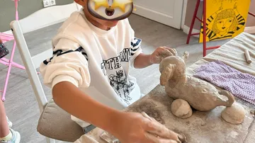 Kind formt Tonfigur am Kunsttisch.