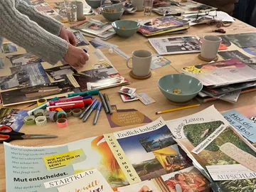 Eine Person arrangiert Zeitschriften und Materialien auf einem Tisch.