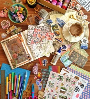 Craft supplies and scrapbook on wooden table.