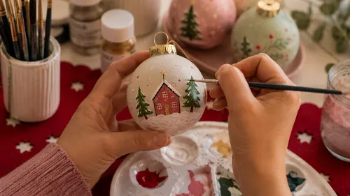 Hands painting design on Christmas ornament.
