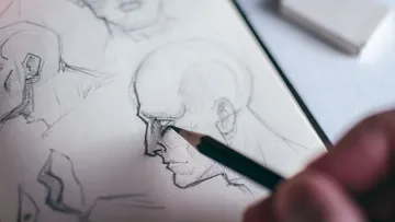 Hand sketching face on paper.