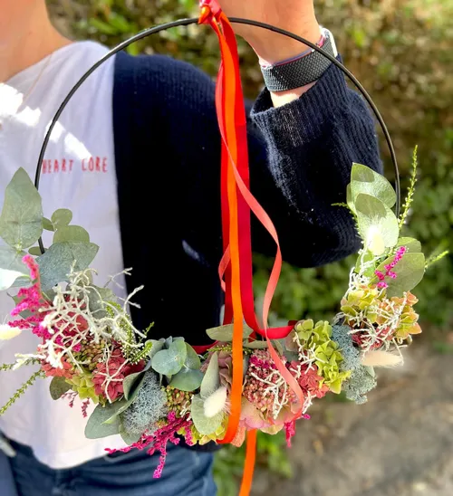 Hand hält Blumenkranz im Freien.