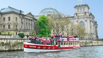 Boot mit Touristen nahe historischem Gebäude.