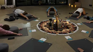 People doing yoga pose around decorative circle.