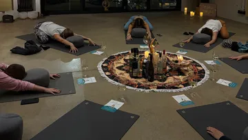 Menschen machen Yoga um ein dekoratives Mittelstück.