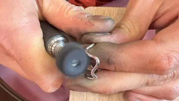 Hands polishing ring with rotary tool.