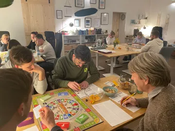 Gruppe spielt ein Gesellschaftsspiel in einem modernen Raum.