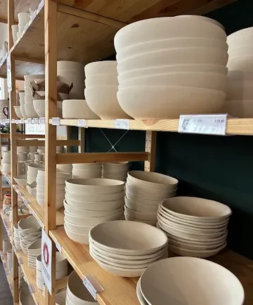 Weiße Schalen auf Holzregalen gestapelt.