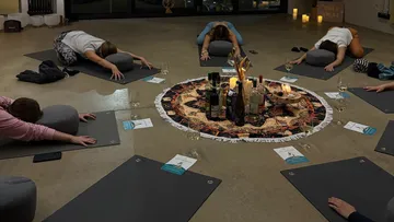 Personen machen Yoga im Kreis drinnen.