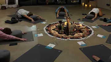 Menschen machen Yoga um einen Kerzenmittelpunkt.