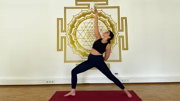 Frau hält Wein während Yoga-Pose drinnen.