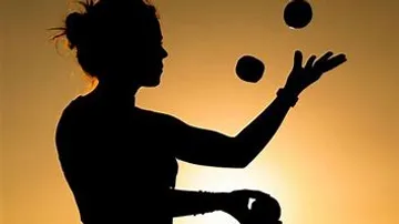 Silhouette of juggler with balls at sunset.