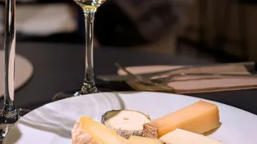 Cheese platter with wine on table.