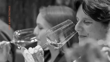 Women tasting wine in a dim setting.