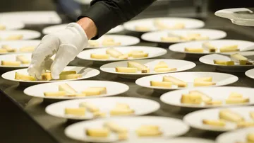 Gloved hand arranging cheese on plates.