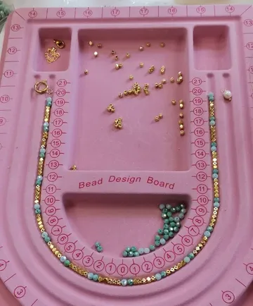 Perlen auf rosa Designbrett angeordnet.