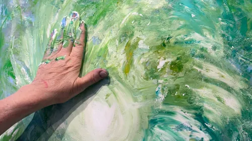 Hand smearing paint on multicolored canvas