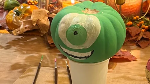 Green pumpkin painted with a monster face.
